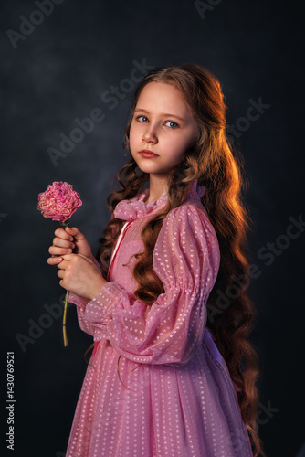 Obraz na płótnie Beautiful girl in a pink dress with a peony flower on a dark background. Romantic, festive image w salonie