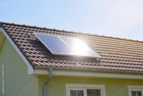 Small solar panel on house rooftop. Sunlight reflects on solar home cell system. Eco industry, green energy innovation, alternative electricity source, clean power generation. Residential building 