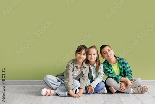 Cute little friends sitting near green wall