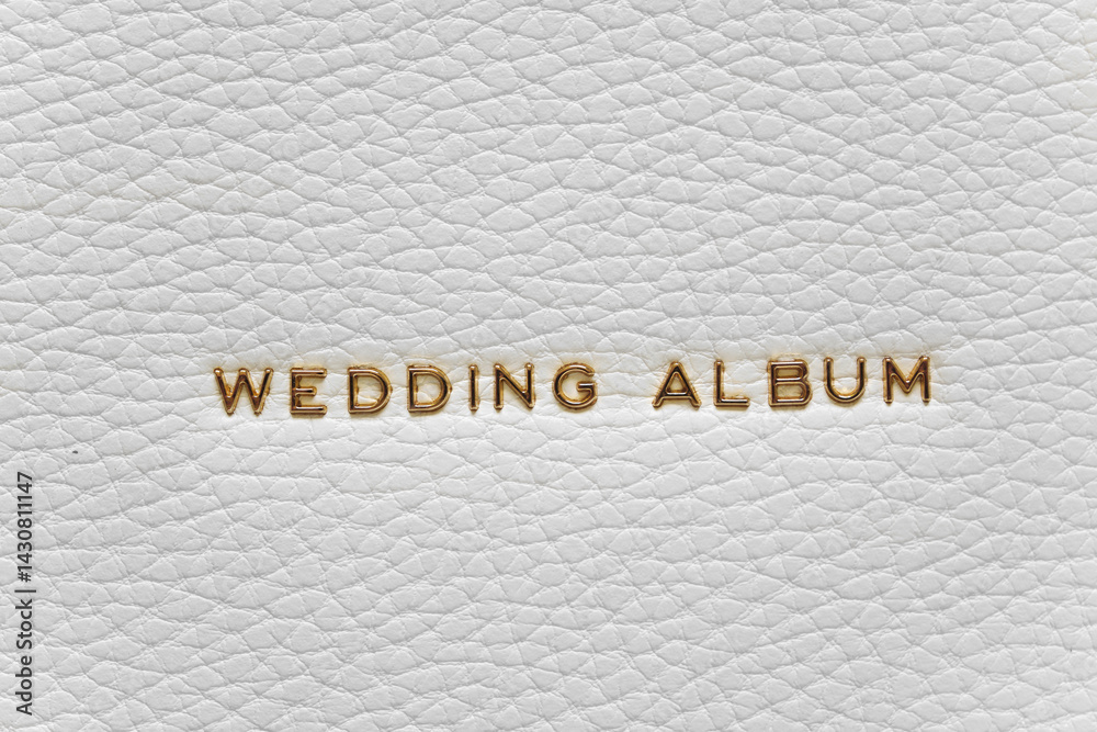 The inscription Wedding Album in gold letters on the white leather cover of book