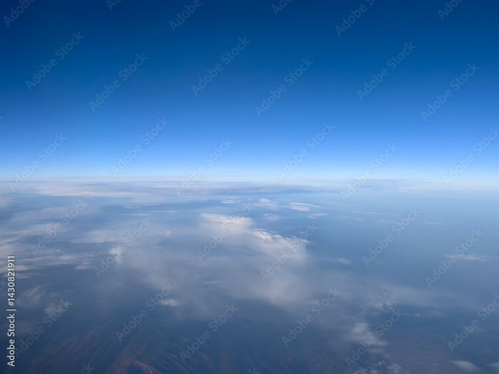 Fototapeta premium View from the porthole to the blue horizon and the earth under the clouds