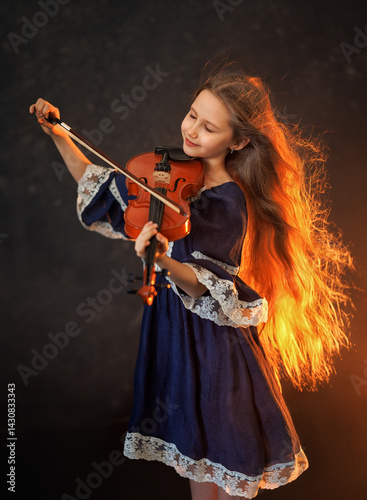Obraz na płótnie Portrait of a beautiful girl with developing long hair and a violin on a dark background in the studio. Music and art w salonie
