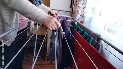 A woman hangs washed clothes on the side of the room