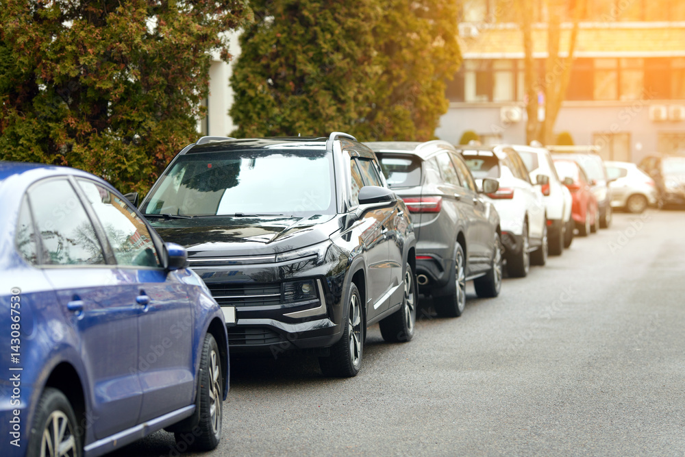 Tight roadside parking, multiple cars lined up in row, downtown space limitations. Cars parked close together in crowded urban area, challenge of limited downtown parking, dense city infrastructure