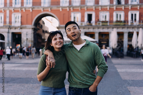 Bilde på lerret Smiling couple pausing in charming European square, looking up with awe and joy,