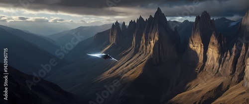 Falcon gliding over jagged mountain cliffs with cold crisp air and wispy clouds rolling through deep valley photo