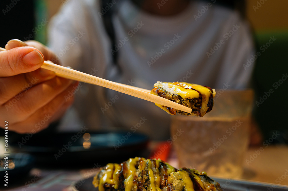 Customer savoring hot sushi roll with chopsticks, experiencing the rich flavors of japanese cuisine in a restaurant setting