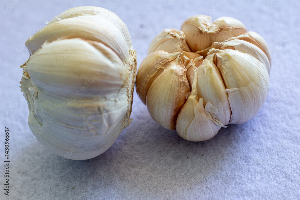 Obraz premium Fresh whole garlic bulbs on a soft white surface, ideal for culinary and health-related content