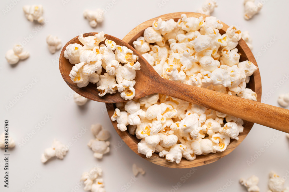 White salty or sweet popcorn in wooden spoon on light gray background top view. Scattered cornflakes, food for movie or cinema. Tasty snack, party snack White salty or sweet popcorn in wooden spoon on light gray background top view. Scattered cornflakes, food for movie or cinema. Tasty snack, party snack