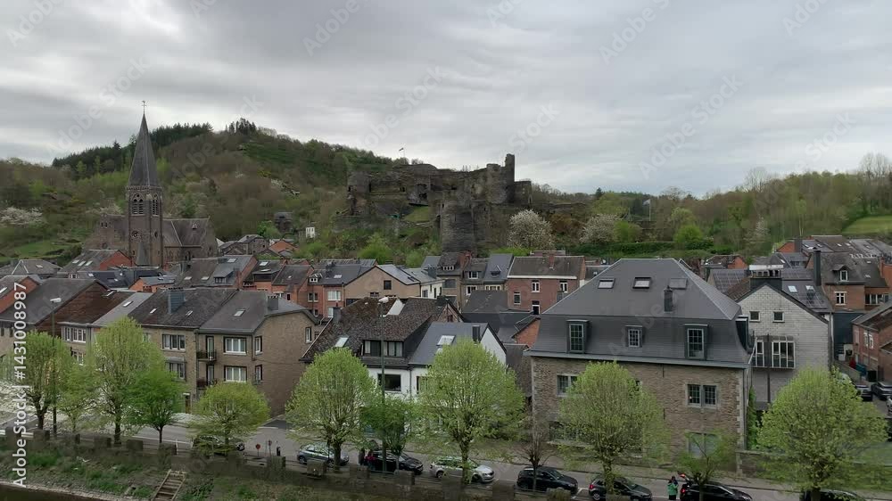 Panoramic, scenic skyline view of La Roche en Ardenne city. Belgian flag is waving on top of  a ruined medieval feudal castle. Saint Nicholas church tower. La Roche en Ardenne, Belgium