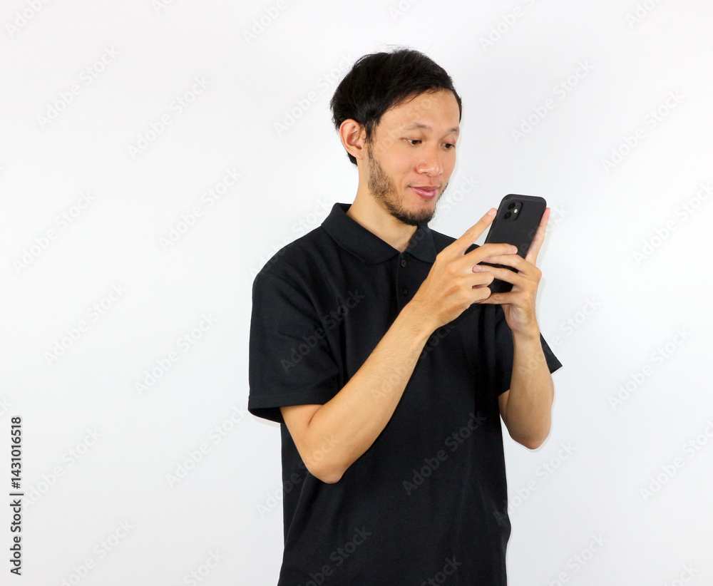 Man Using Mobile Phone, Smiling Indoors in Studio with White Backdrop Man Using Mobile Phone, Smiling Indoors in Studio with White Backdrop