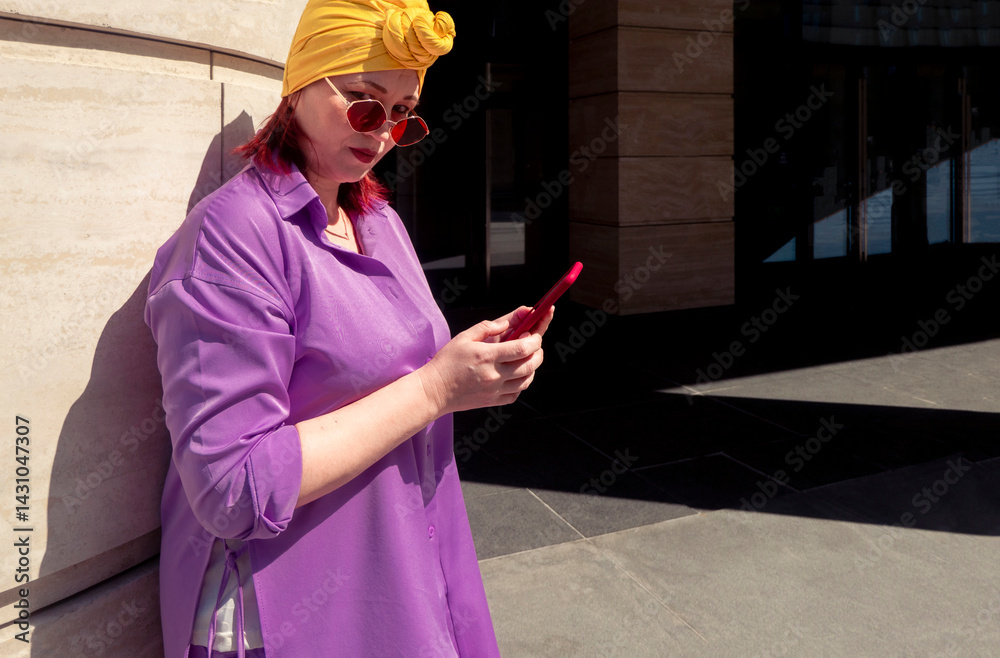Happy and funny cool lady with fashionable clothes on dark background look to the phone seriously and thoughtfully - adult asian with extravagant style, concepts about lifestyle, fasion and elderly