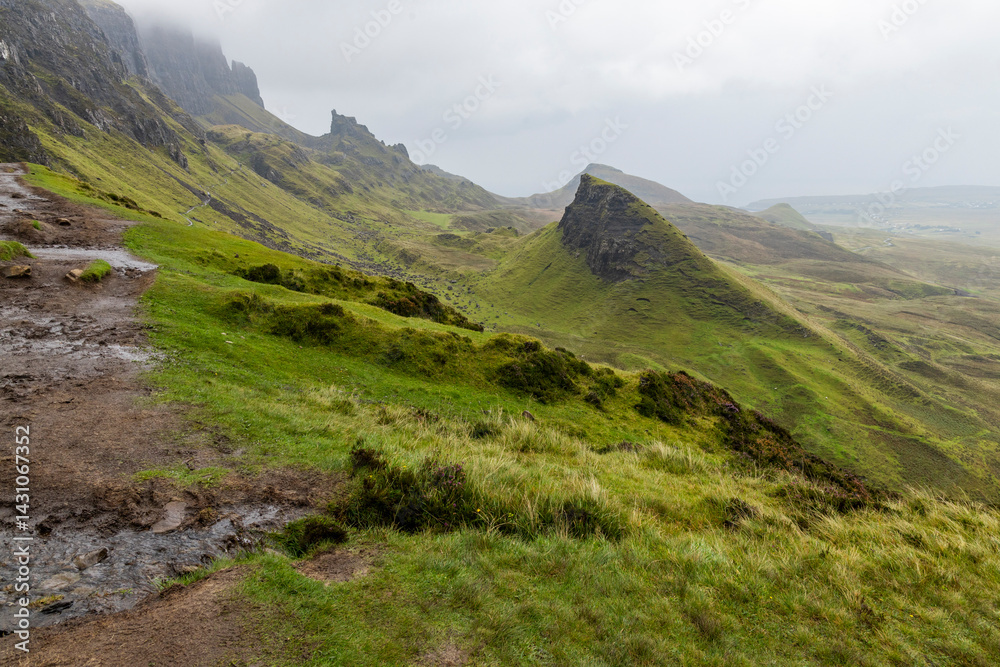 Fototapeta premium The Quiraing, Isle of Skye lush green landscapes, pure air, dramatic cliffs. A surreal trail through wild nature, perfect for trekking, silence, breathing untouched beauty, mystical rock formations.