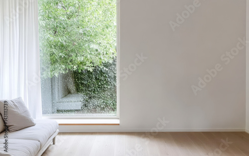 Modern living room with large window and greenery view during rainy day