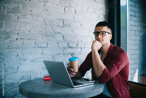 Pensive man with laptop having coffee in cafe