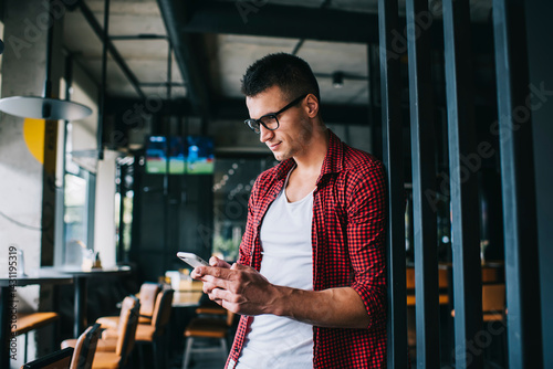 Smiling male browsing smartphone in cafe