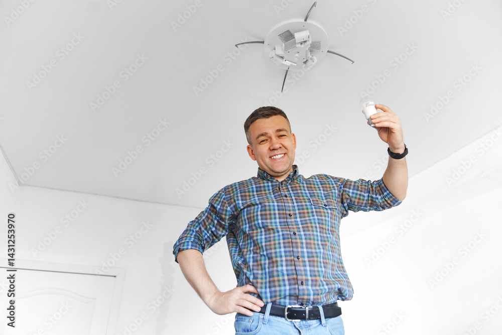 A cheery man in a plaid shirt replacement of light bulbs in a ceiling lamp