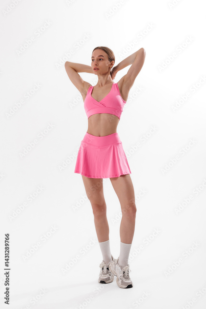 Fototapeta premium Young woman in pink activewear poses confidently during indoor photo shoot focused on fitness and style