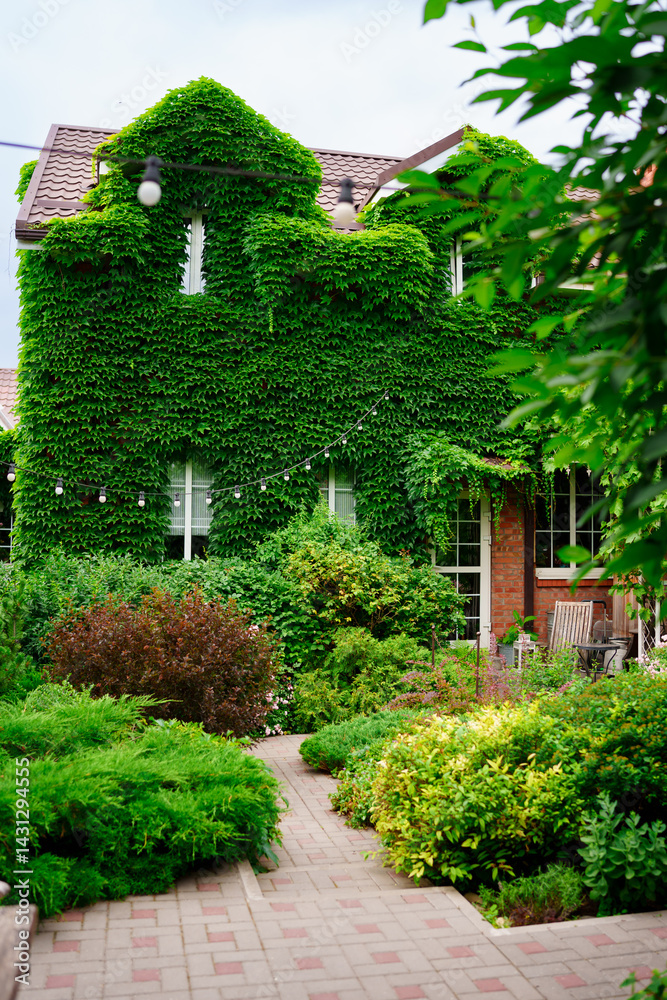 a house and a courtyard of a country house, braided with greenery.