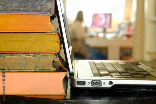 Laptop computer and stack of books ,blurred office in the background.Beat the clock,office work,research,education concept.Free copy space.