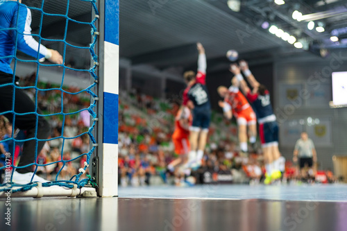 Detail of handball goal post with net and handball match in the background..handball;
