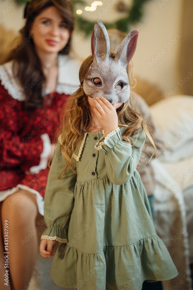 Little girl in a green dress and a carnival hare mask. Festive masquerade.