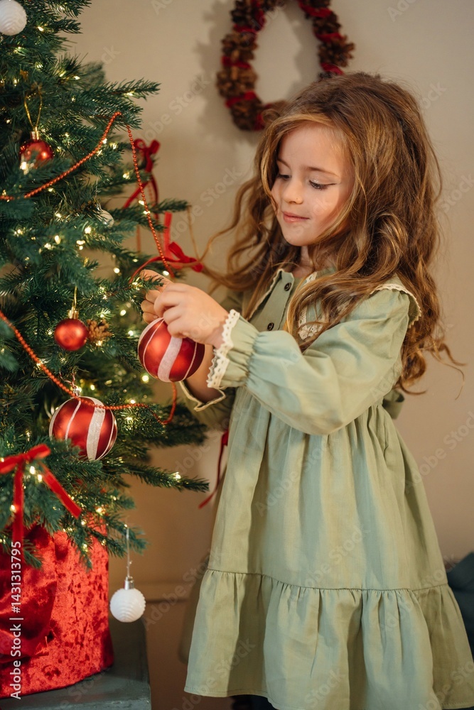 Beautiful little girl decorates a christmas tree