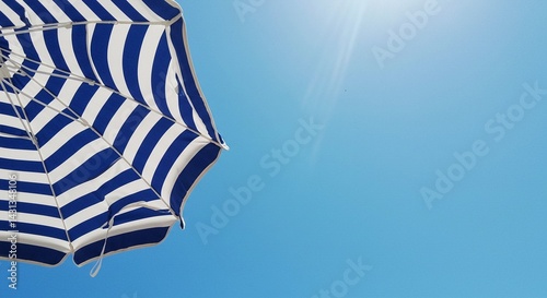 Striped beach umbrella against blue sky, sunny vacation scene