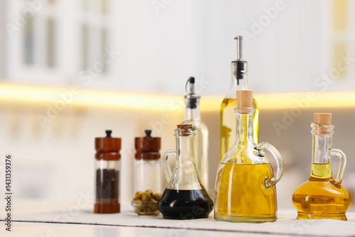 Bottles of salad dressings, salt, pepper and olives on white table in kitchen