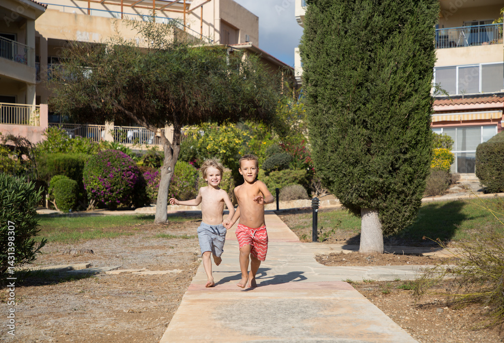 Obraz premium boys 5 - 6 years old barefoot, in shorts, cheerfully running races in the park, doing sports outdoors . concept of active games and healthy lifestyle. Who is faster. healthy lifestyle and recreation
