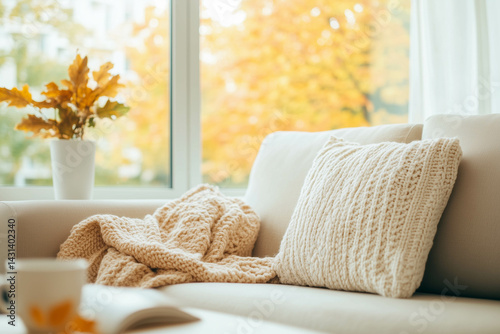 Obraz na płótnie A cozy and warm living room with a sofa and blanket, with a view of the fall foliage. w salonie