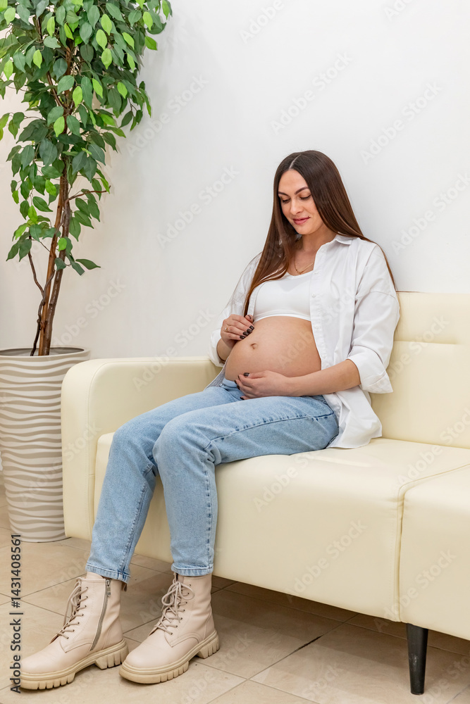 Close up pregnant woman gently touching her belly, sitting on sofa in a cozy home, showing maternal love and anticipation. Captures love, care, and connection during pregnancy. Footage with copy space