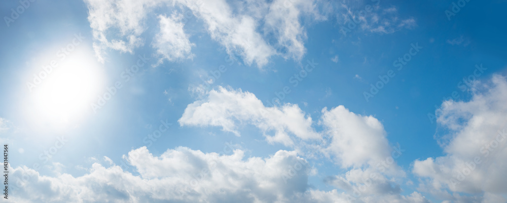 sky background with light shine from sun at the left and fluffy clouds