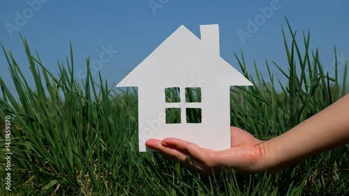 Paper house in the palm of a woman's hand. Symbol of housing and the future.