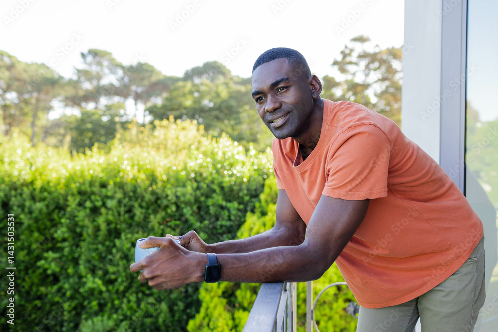Leaning African American man holding coffee mug on balcony railing, wearing smartwatch, copy space Leaning African American man holding coffee mug on balcony railing, wearing smartwatch, copy space