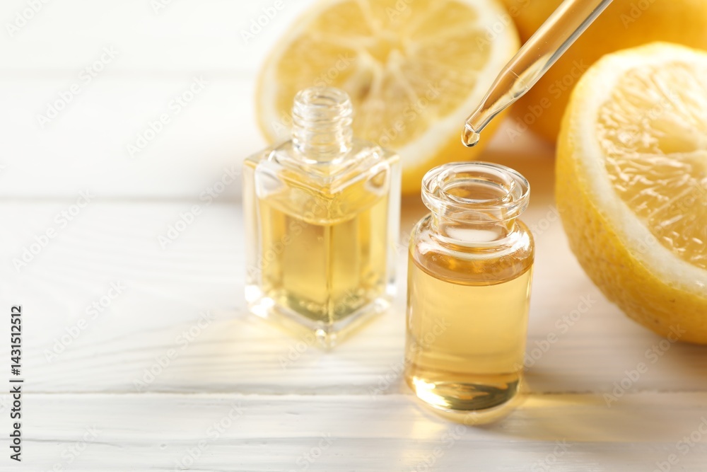 Dripping aromatic essential oil from pipette into perfume bottle and lemons at white wooden table, closeup. Space for text Dripping aromatic essential oil from pipette into perfume bottle and lemons at white wooden table, closeup. Space for text