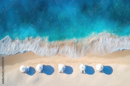 Aerial view of beach umbrellas on white sand, turquoise ocean waves gently lapping the shore photo