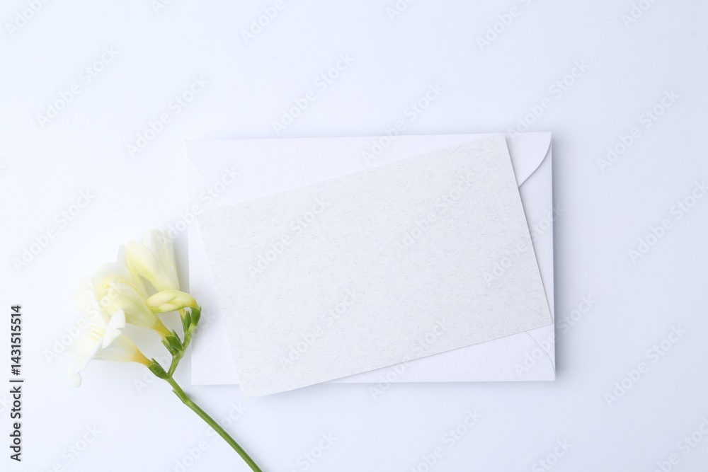 Blank greeting card, paper envelope and flower on white background, flat lay Blank greeting card, paper envelope and flower on white background, flat lay