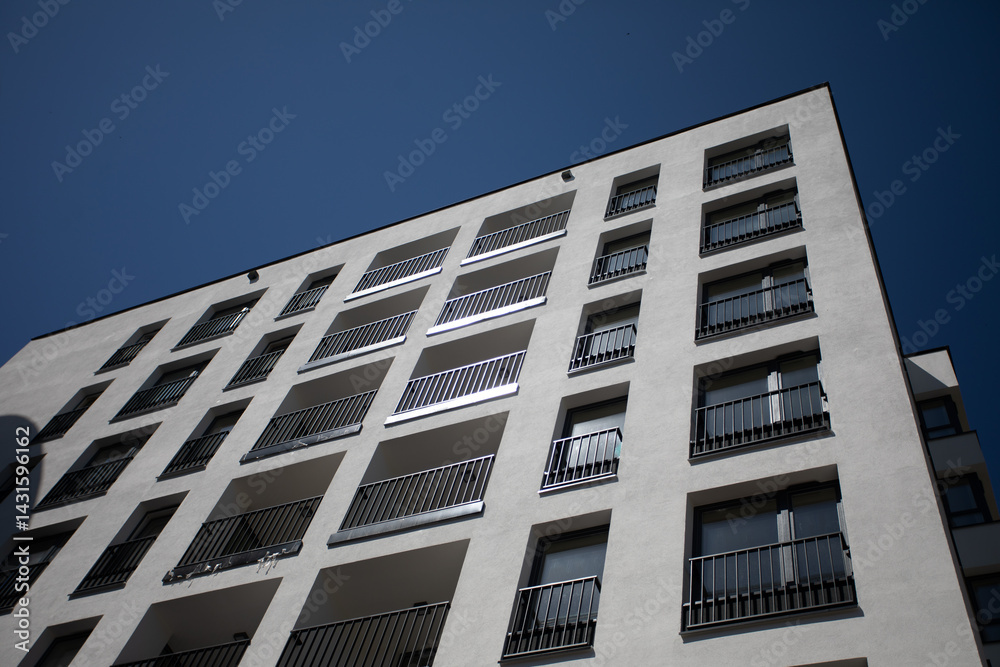 A Modern Apartment Building Stands Tall Against a Sleek and Clear Blue Sky Above It A Modern Apartment Building Stands Tall Against a Sleek and Clear Blue Sky Above It