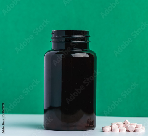 Black Plastic Bottle with Supplement Pills Against Green Background