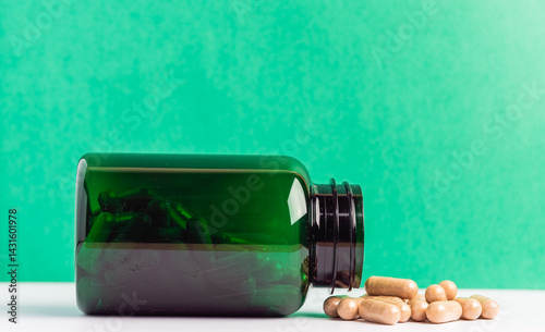 Green Bottle with Capsules on White Surface Against Green Background
