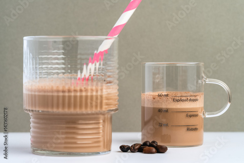 Two Coffee Beverages in Unique Glasses With a Pink Straw and Coffee Beans