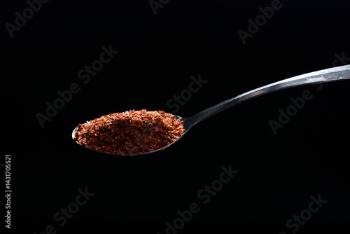 Close up cayenne spices on spoon isolated on black background.