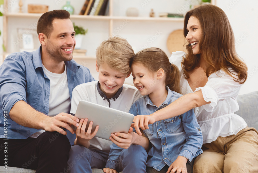 Parents And Children Using Tablet Computer Sitting On Sofa Watching Film Together At Home. Family Weekend Concept Parents And Children Using Tablet Computer Sitting On Sofa Watching Film Together At Home. Family Weekend Concept