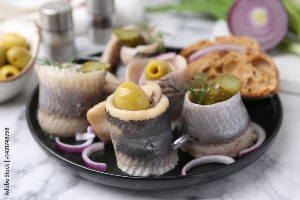 Delicious herring rolls with olives, pickles, dill, onion and bread pieces on light marble table, closeup Delicious herring rolls with olives, pickles, dill, onion and bread pieces on light marble table, closeup