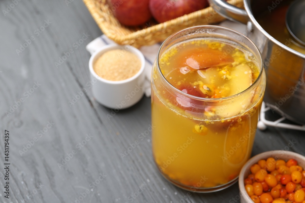 Tasty compot in glass jar and ingredients on grey wooden table, closeup. Space for text Tasty compot in glass jar and ingredients on grey wooden table, closeup. Space for text