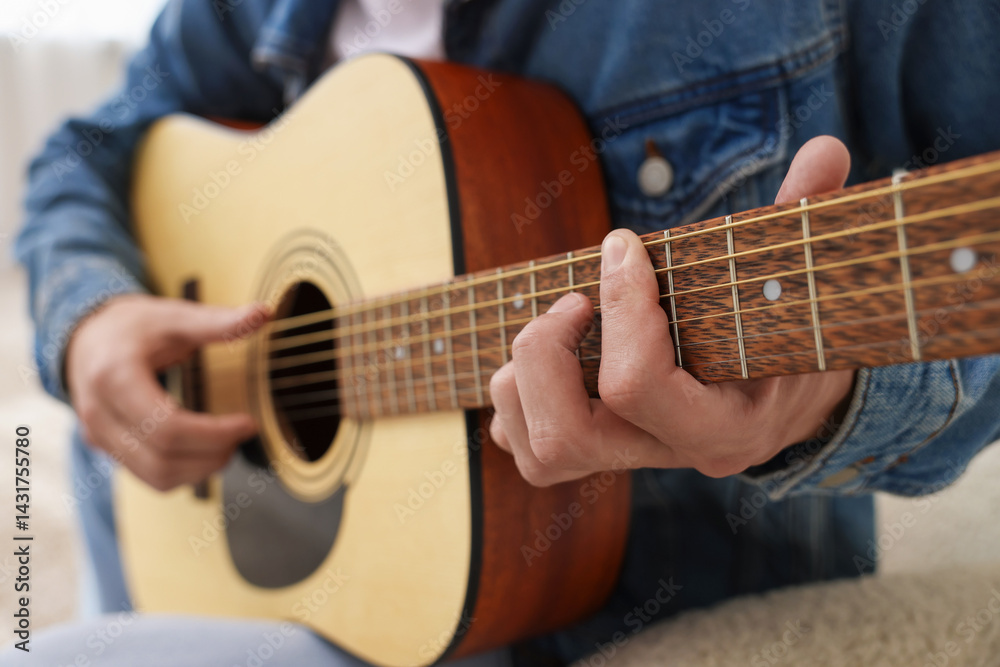 Obraz premium Man playing guitar on armchair indoors, closeup
