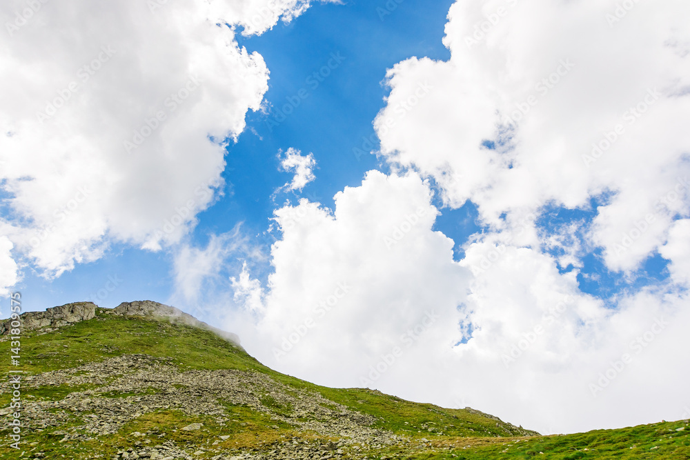 landscape with mountain and blue sky with clouds. alpine adventure. steep hill with stones and grass. beautiful nature of romania in summer