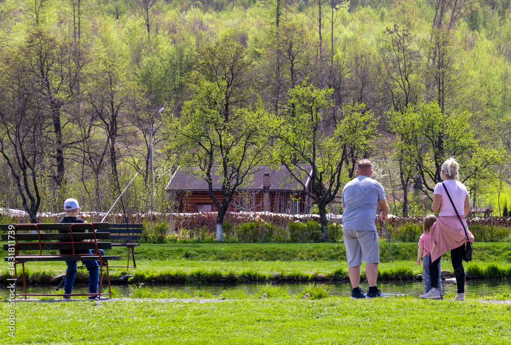 A family fishing on the shore of a lake seen from behind