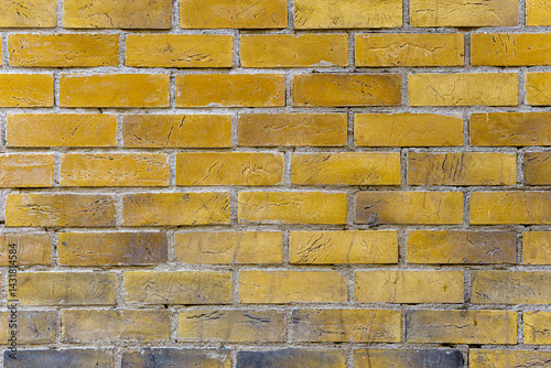 A brick wall with a yellow color. The bricks are arranged in a pattern.